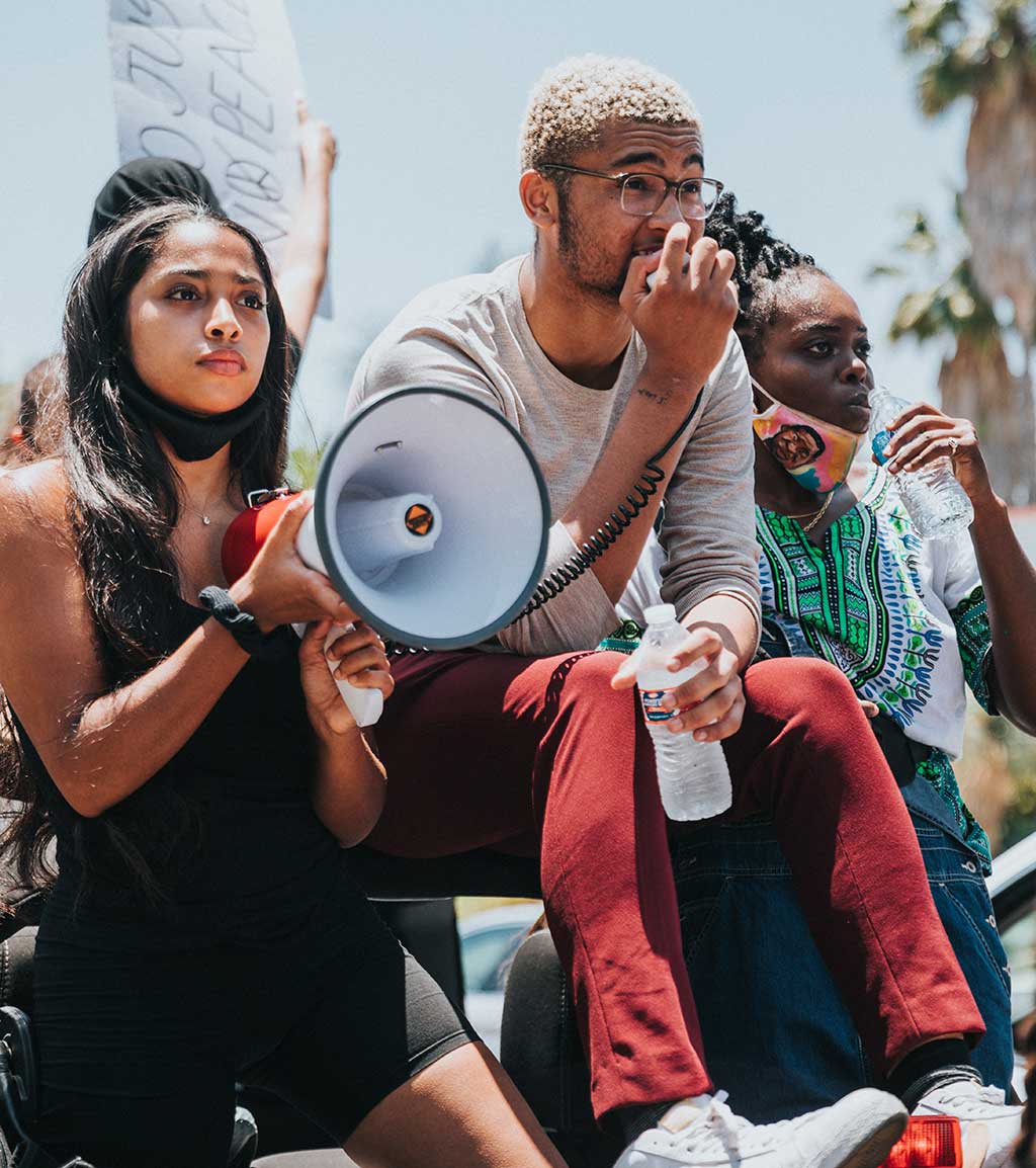 Drei junge Menschen auf Demonstation mit Megafon