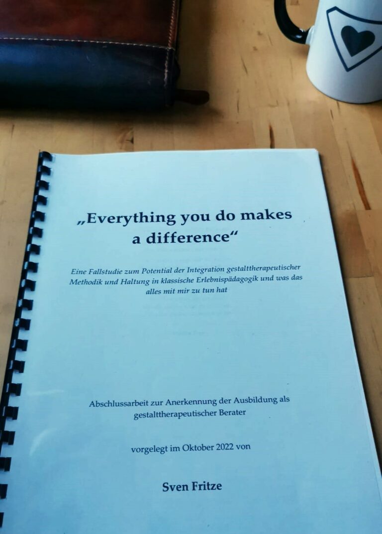 Nahaufnahme einer Mappe mit Schriftzug "Everything you do makes a difference" auf einem Holzuntergrund liegend.