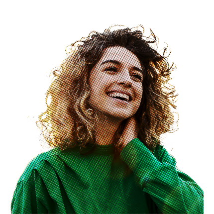 Frau in grünem Sweatshirt und mit lockigen braun-blonden Haaren greift sich lachend in den Nacken.