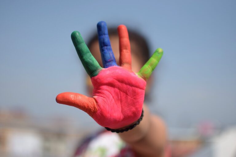 Person streckt eine bunte Hand abwehrend in die Kamera.